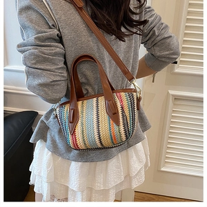 Détail d'un sac seau tissé coloré avec poignées et bandoulière en cuir marron