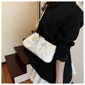 Detail of white pleated patent leather shoulder bag with pearl heart charm and silver metal