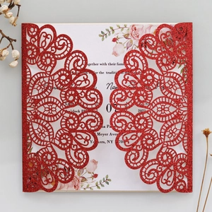 Detail of red glitter laser-cut invitation cover with intricate hollow peacock floral pattern