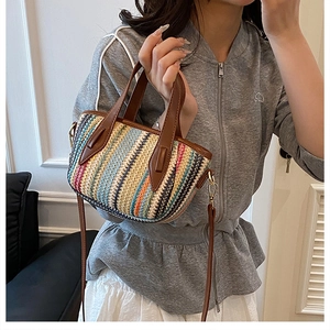 Détail d'un sac tissé multicolore avec poignées en cuir marron et bandoulière