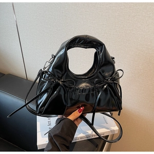 Détail du sac à main en cuir verni noir brillant avec nœuds et poignée ronde