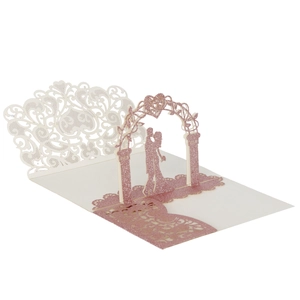 Macro shot of 3D laser-cut wedding invitation featuring pink glitter arch and couple silhouette