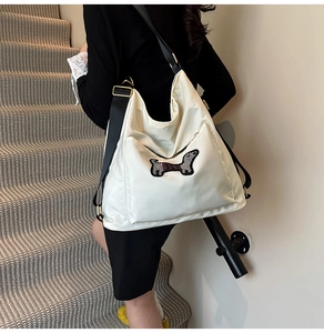 Detail of white nylon messenger bag with cute dachshund patch and black wide strap