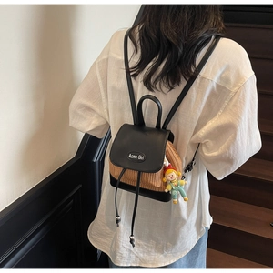 Mini-Rucksack aus Leder und Geflecht mit Puppenanhänger auf einer minimalistischen Treppe