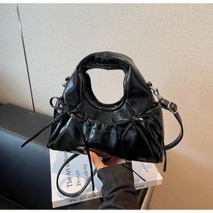 Détail du sac à main en cuir verni noir brillant avec nœud et poignée évidée