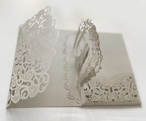 Macro view of detailed laser-cut white wedding invitation with 3D pop-up silhouette