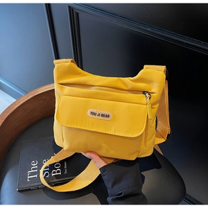 Dettaglio ravvicinato di una borsa a tracolla in nylon giallo su sedia in pelle