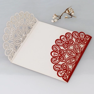 Detail of laser-cut wedding invitation featuring red glitter and elegant lace patterns