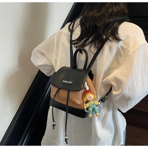 Detail eines gewebten Mini-Rucksacks mit schwarzem Leder und süßem Puppenanhänger
