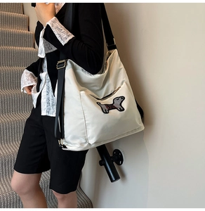 Close-up of cute dachshund embroidery on a cream nylon crossbody bag with black strap