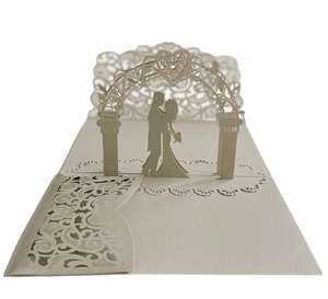 Close-up of 3D pop-up wedding card with laser-cut ivory bride and groom under an arch
