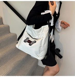 Detail of white nylon backpack featuring a cute dog sequin patch and black straps