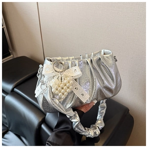 Détail d'un sac à main plissé argenté avec breloque cœur perle et nœud en dentelle