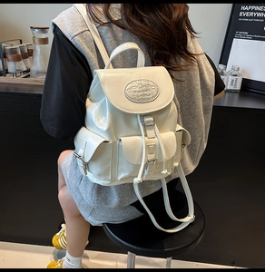 Vue de dos d'un sac à dos élégant en cuir blanc brillant porté par un mannequin en café