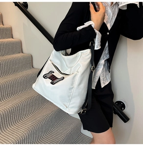 Side view of white nylon tote bag featuring a sequined puppy patch and black strap