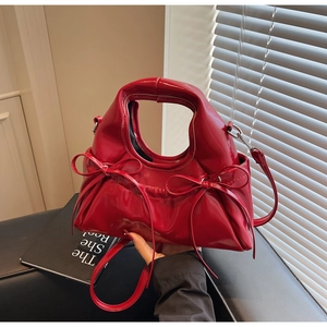 Détail d'un sac à main en cuir verni rouge brillant avec nœuds décoratifs fins