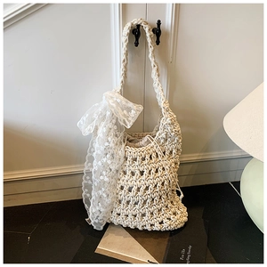 Close-up of woven cream bucket bag featuring textured patterns and oversized lace bow detail