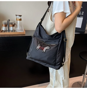 Detail of black nylon tote bag with a stylish embroidered dog patch and shoulder straps
