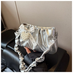 Detail of silver ruched handbag with pearl heart and lace bow charm on black leather