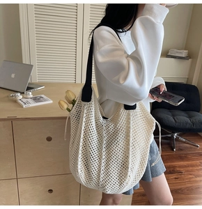Gros plan du sac fourre-tout tissé beige avec large bandoulière noire et maille ajourée