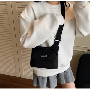 Dettaglio borsa a tracolla nera con ampia cinghia regolabile e placca logo YOU JI BEAR