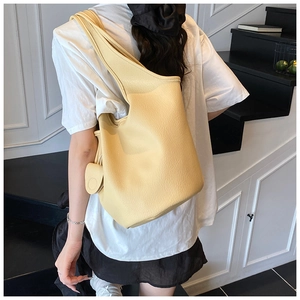 Detail view of cream yellow pebbled leather bucket bag with circular coin pouch accessory