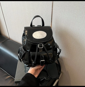 Vue détaillée du sac à dos en cuir verni noir avec logo métallique et cordon serrage