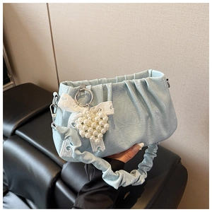 Détail du sac à bandoulière froncé bleu clair avec nœud en dentelle et cœur perlé