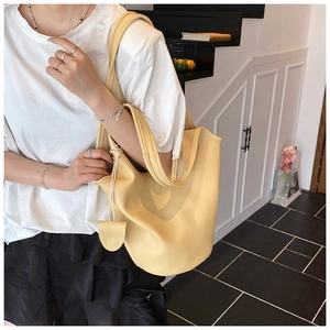 Detailed macro view of light yellow litchi pattern leather bucket bag with side rope detail