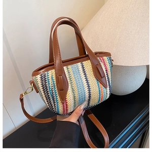 Détail du sac seau en paille tissée colorée avec poignées en cuir marron et boucles dorées