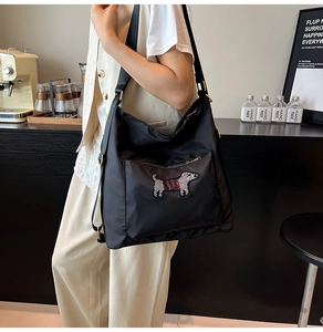 Detail of black nylon tote bag with sequin puppy embroidery shown in a cafe setting