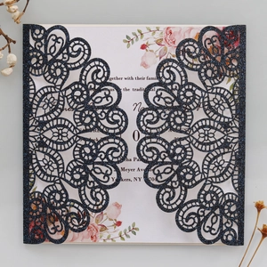 Macro shot of glittery dark blue laser-cut lace wedding invitation with floral insert
