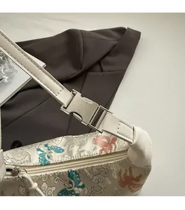 Detail of silver metallic buckle and floral butterfly embroidery on a white satin bag