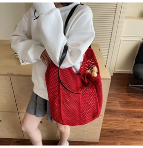 Détail du sac à bandoulière en tricot ajouré rouge avec bandoulière en cuir noir