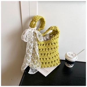 Detail of yellow woven bucket bag with large white lace bow and drawstring inner liner