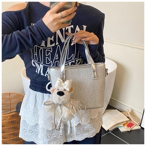 Details der silbernen Pailletten-Handtasche mit süßem Plüschhund-Anhänger und Ledergriff