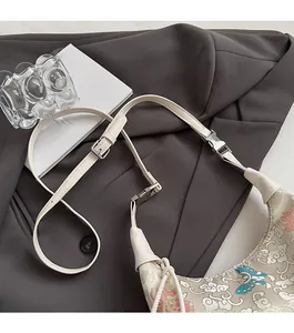 Detailed close-up of embroidery pattern and soft leather strap on cream hobo bag