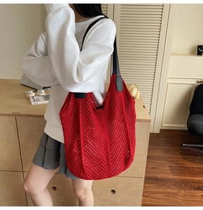 Détail du sac cabas au crochet rouge montrant la maille en losange et les anses en cuir noir