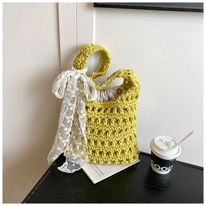 Detail of yellow knit bucket bag with a white lace bow and drawstring inner pouch
