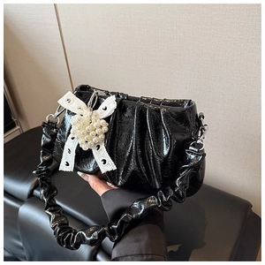 Close-up of black ruched bag with white lace bow and heart-shaped pearl charm detail
