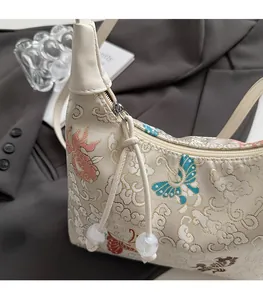Close-up of traditional Chinese embroidery and smooth metal zipper on beige canvas bag