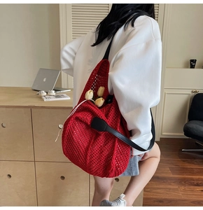 Gros plan du sac cabas en crochet rouge avec bandoulière en cuir noir et cordon blanc