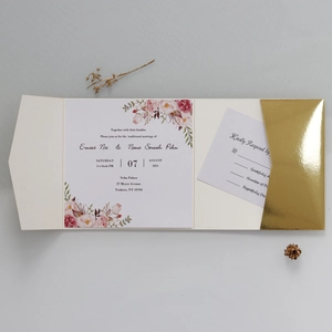 Flat lay of floral wedding invitation with RSVP card in a gold mirror pocket sleeve
