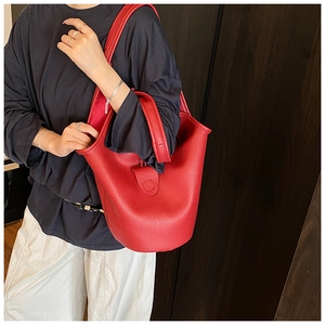 Detail view of red lychee grain leather bucket bag with wide shoulder strap