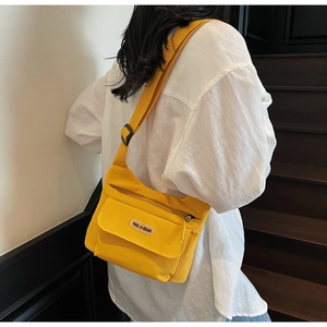 Vista dettagliata della borsa a tracolla in tela gialla con la toppa circolare del logo YOU JI BEAR