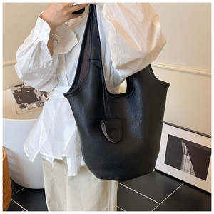 Minimalist black pebble leather bucket bag styled with a white shirt and beige trousers
