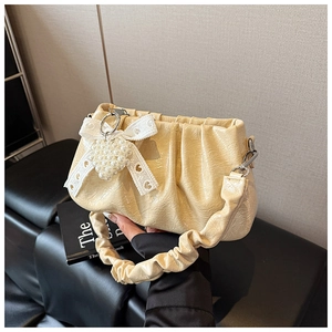 Detail of cream pleated shoulder bag featuring pearl heart pendant and lace bow