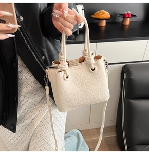 Detail of cream white lychee leather bucket bag with a stylish knotted handle design