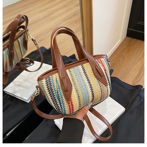 Détail du sac seau en paille tressée à rayures avec poignées en cuir et fermeture