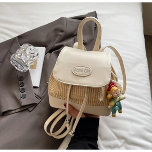 Detailansicht beige Strohrucksack mit Acme Girl Prägung und süßem Puppen-Anhänger